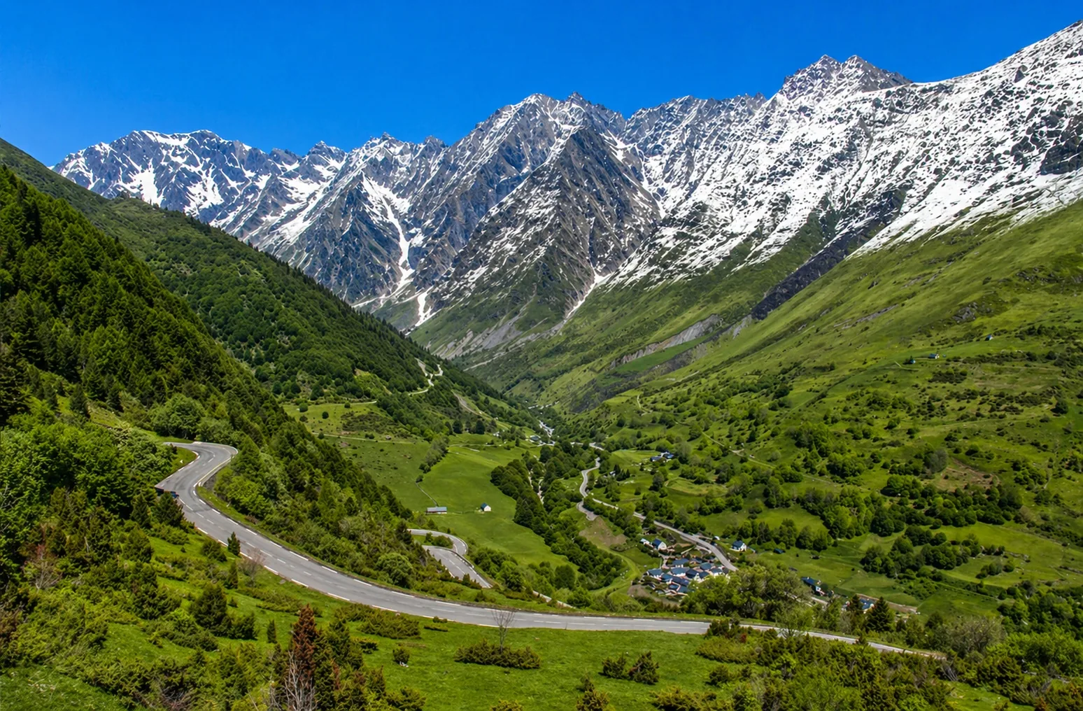 Vue de haute vallée pyrénéenne autour d’Aragnouet et du massif du Néouvielle avec route de montagne, reliefs et sommets enneigés