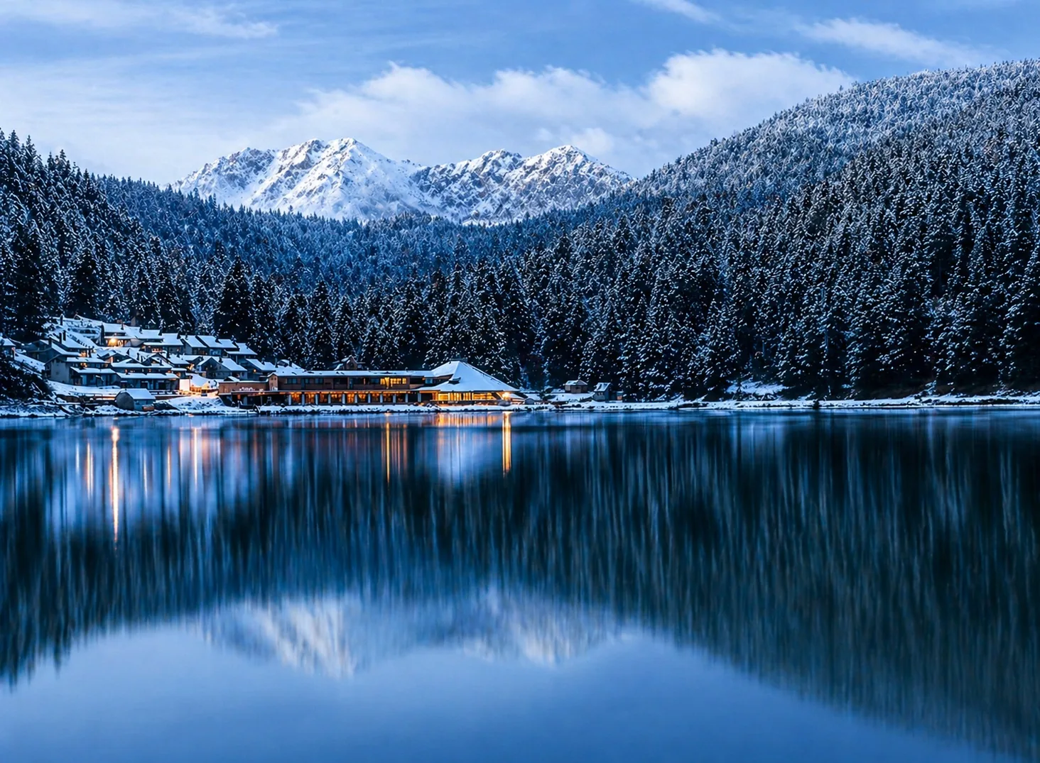 Vue hivernale du lac de Payolle avec forêt enneigée, reflets sur l’eau et sommets pyrénéens