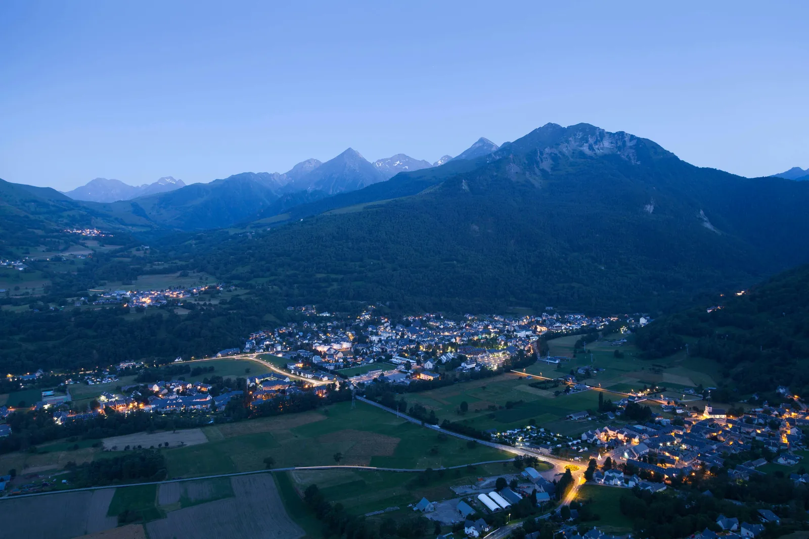 Vue aérienne de Luz-Saint-Sauveur au crépuscule dans la vallée de Luz, entre village, montagne et accès aux Grands Sites des Hautes-Pyrénées
